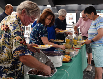 volunteers serving themselves up a pot luck dinner